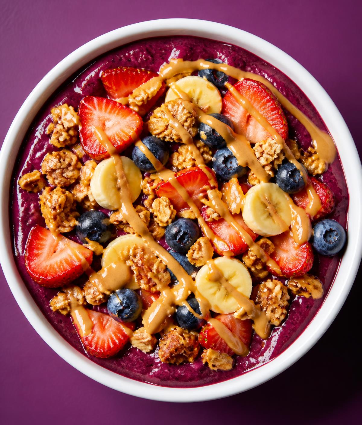 Açaí bowl topped with strawberry, banana, blueberries, granola and peanut butter